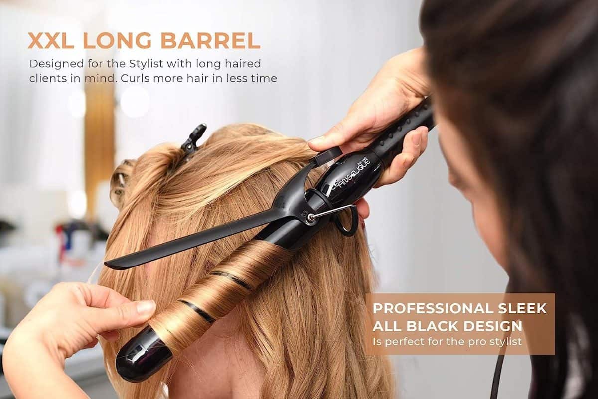 A stylist uses the Ultimate Pro Clip Curling Iron 1" with an XXL long black barrel to curl a client’s blonde hair in a salon, highlighting its professional design and advanced features.