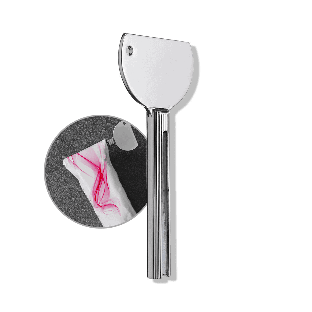A large silver Color Tube Squeezer with a round handle is shown cutting open a white plastic package with pink lines.