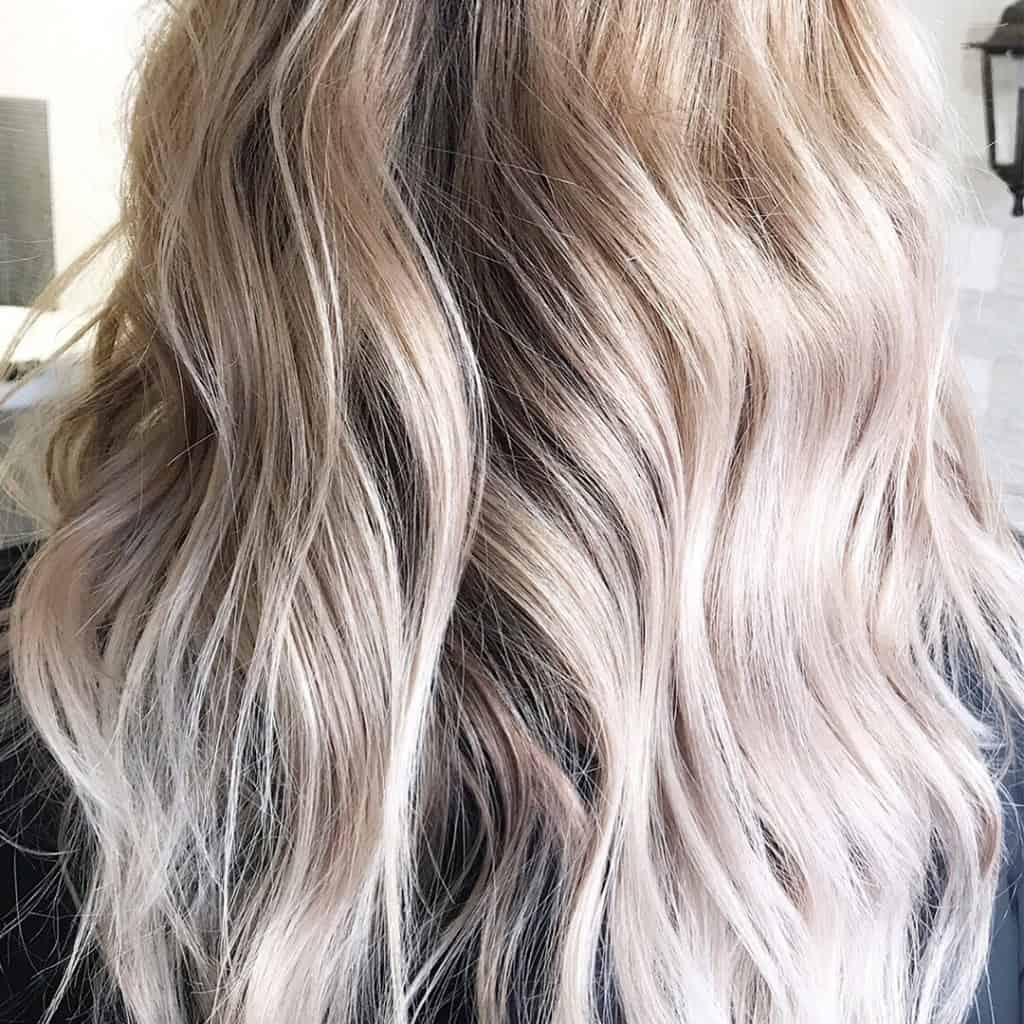 Wavy, shoulder-length hair in a light blonde shade with darker roots, shown from the back.