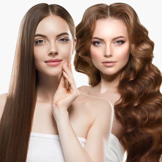 Two women with fair skin and long brown hair; one has straight hair and touches her face, while the other has voluminous, wavy hair. Both wear white, off-shoulder tops.