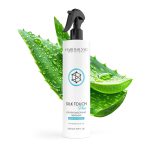 A bottle of Silk Touch Plus Keratin Advanced Formula is displayed in front of two aloe vera leaves with water droplets.