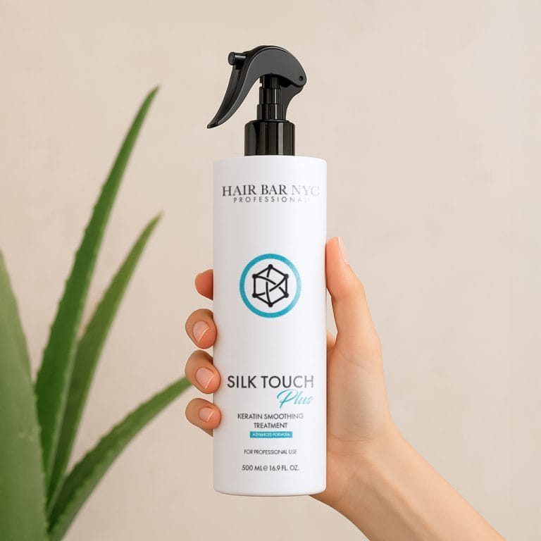 A hand holds a bottle of Silk Touch Plus Keratin Advanced Formula with a spray nozzle, with a green plant in the background.